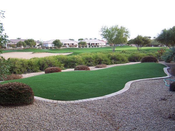 Artificial grass lawn with gravel border landscaping adjacent to golf course fairway and sand bunker in Southwest residential community