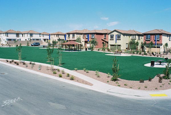 Artificial turf installation at Southwest residential community common area with gazebo, young trees, and desert landscaping