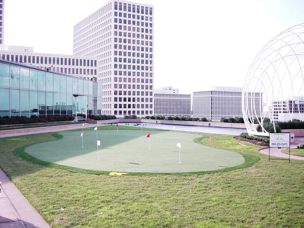 Outdoor putting green with multiple flags installed on rooftop terrace at downtown high-rise office complex