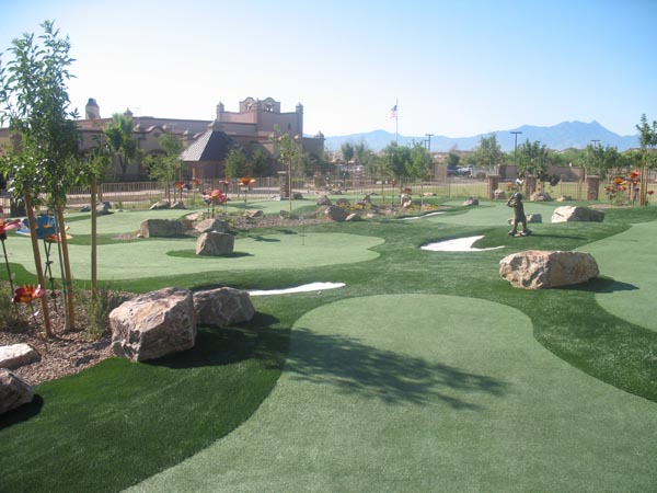 Synthetic turf putting green mini golf course with boulder landscaping and mountain views at Southwest resort community
