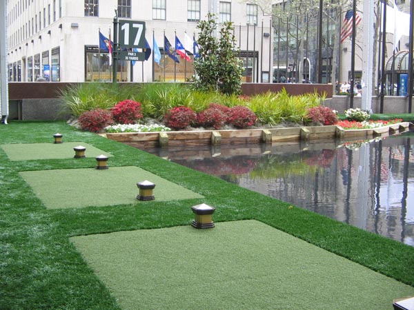 Artificial turf tee lines with solar path lights at urban rooftop or plaza golf venue in downtown city setting