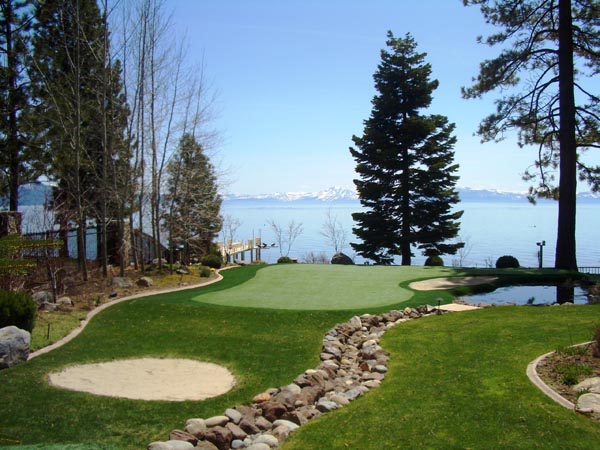Backyard putting greens with sand bunkers and rock border overlooking Lake Tahoe with snow-capped mountain views