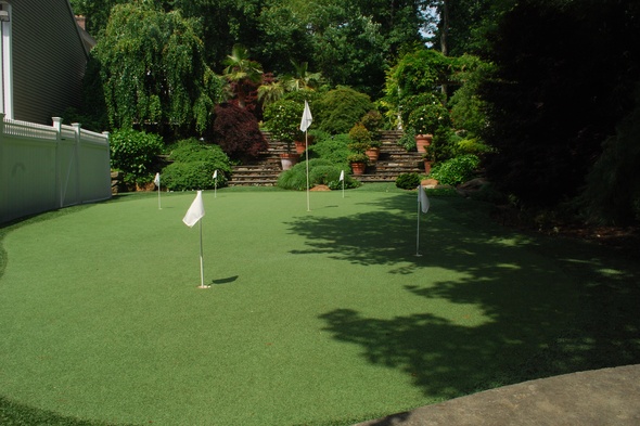 Albuquerque Synthetic grass golf green with flags in a landscaped backyard