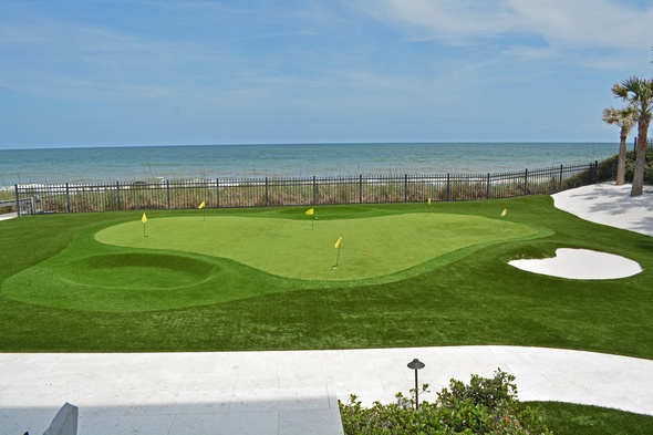 Albuquerque Synthetic grass golf green by the sea with yellow flags and a sand bunker
